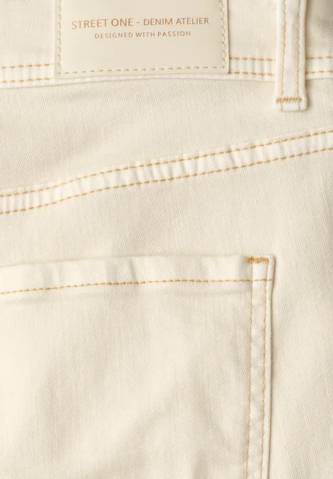 Close-up van achterzijde van een crèmekleurige jeans met zak en sierstiksels
