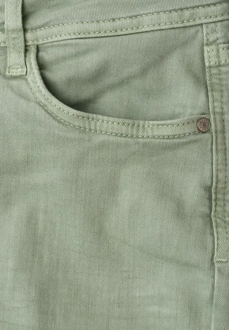 Detailaufnahme einer hellgrünen Jeanshose mit Taschennaht und Metallniete.