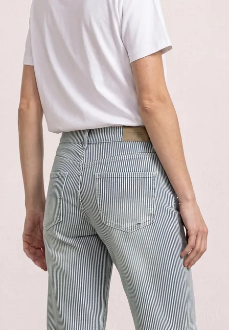 Person von hinten in weißem T-Shirt und hellblauer, gestreifter Jeanshose.