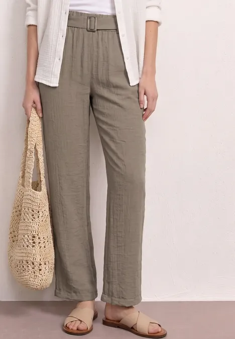 Luftige, hoch geschnittene Hose in Olivgrün mit Gürtel, kombiniert mit Netz-Tasche und beigen Sandalen.