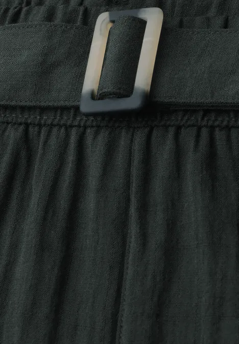 Schwarzer, plissierter Rock mit breitem Gürtel und quadratischer Metallschnalle, Nahaufnahme.