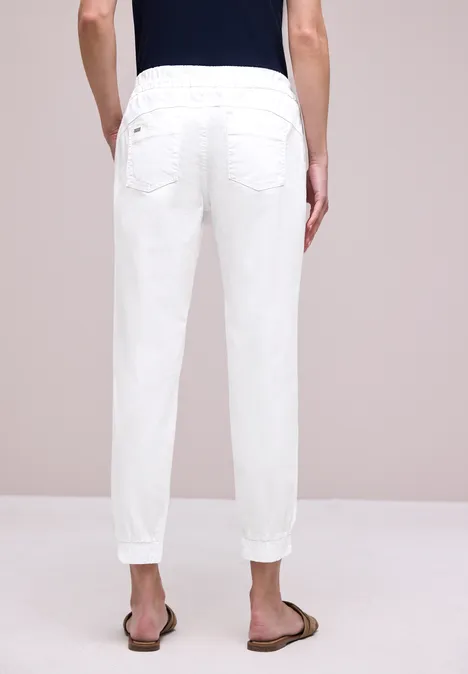 Achteraanzicht van een persoon in witte broek en bruine sandalen.