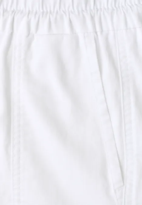 Close-up van een witte broek met elastische tailleband en zijzak.