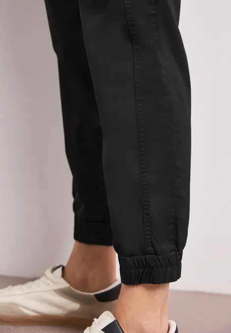 Nahaufnahme von Knöcheln in schwarzen Jogginghosen und weißen Sneakern.