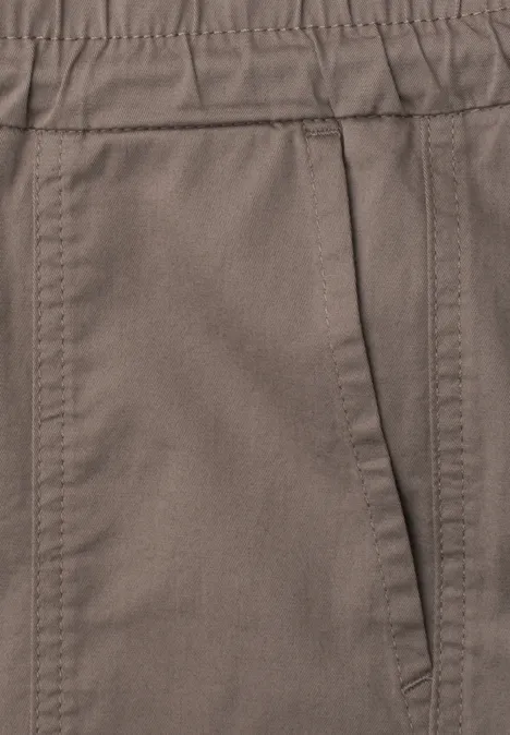 Nahaufnahme einer braunen Hose mit seitlicher Tasche und sichtbaren Nähten.