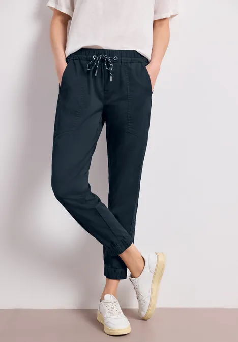 Person trägt schwarze Jogginghose mit Kordelzug und weiße Sneaker