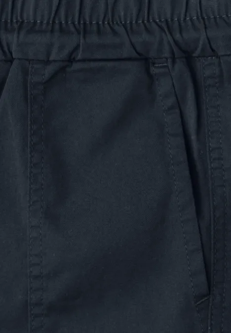 Nahaufnahme einer dunklen Hose mit elastischem Bund und seitlicher Eingriffstasche.