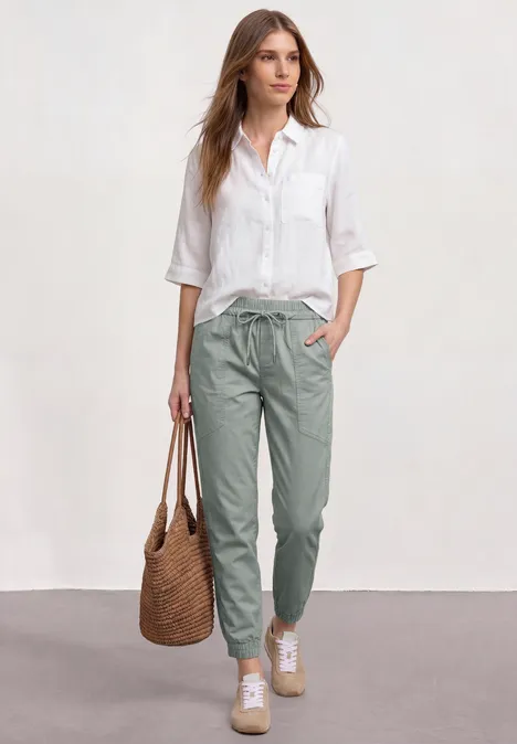 Slim legs broek in een lichtgewicht stof dark mint green Vrouw in wit overhemd en groene broek met gevlochten tas, casual en elegant