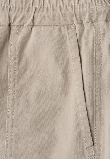 Nahaufnahme einer beigen Hose mit elastischem Bund und seitlicher Tasche