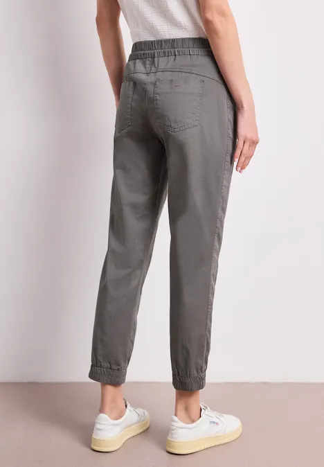 Grijze jogger met elastische taille en enkels, losse pasvorm, gecombineerd met sneakers.