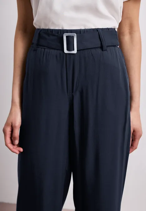 Dunkelblaue, hoch geschnittene Hose mit weitem Bund und weißer, eckiger Gürtelschnalle.