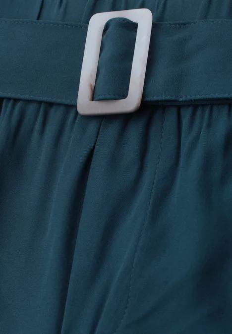 Nahaufnahme eines türkisfarbenen Gürtels aus Stoff mit weißer, rechteckiger Schnalle.