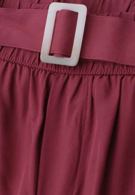 Nahaufnahme eines burgunderroten Kleidungsstücks mit elastischem Bund und weißer Schnalle.
