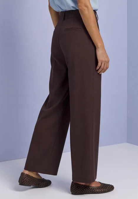 Personne porte un pantalon large marron et des ballerines marron à pois.