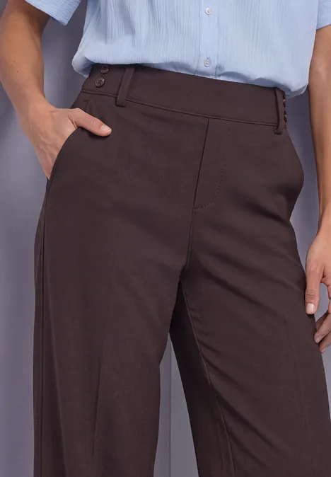 Pantalon femme marron foncé avec poche latérale, associé à une chemise bleu clair.