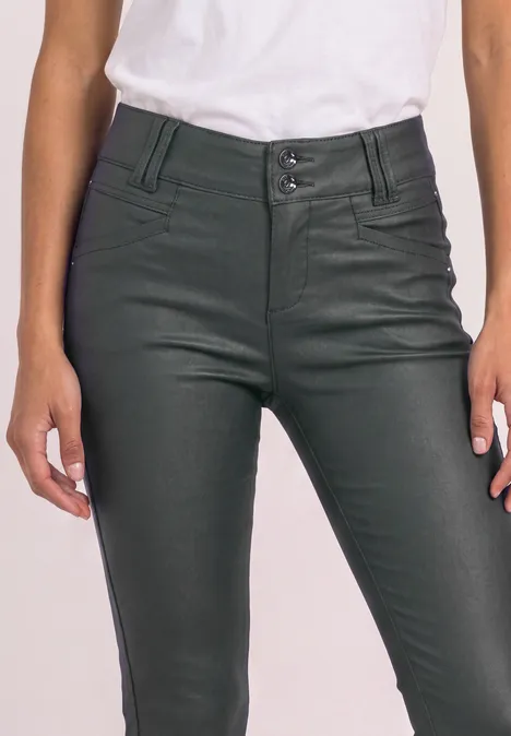 Hochgeschnittene, dunkelgrüne Lederhose und weißes Shirt, enger Sitz an Taille und Hüften.