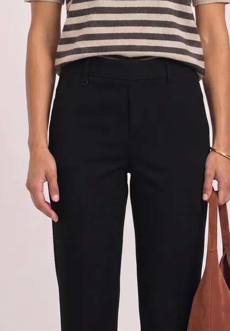 Gestreiftes Shirt, schwarze High-Waist-Hose, Person hält braune Tasche.