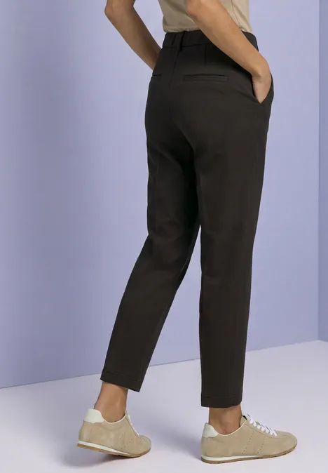 Schmal geschnittene, dunkelgraue Hose mit seitlichen Taschen, getragen mit hellen Sneakern.