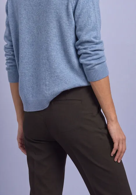 Rückenansicht einer Person in blauem Pullover und dunkler Hose.