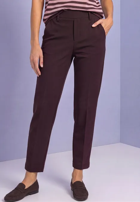 Dunkelbraune, knöchellange Stoffhose mit geradem Schnitt und Loafers.