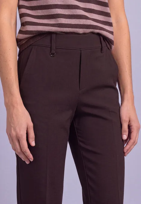 Dunkle, schmal geschnittene Hose mit Bügelfalte, kombiniert mit gestreiftem Top.
