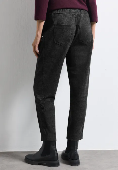 Schwarze, schmal zulaufende Hose mit Gesäßtaschen, kombiniert mit schwarzen Stiefeletten.