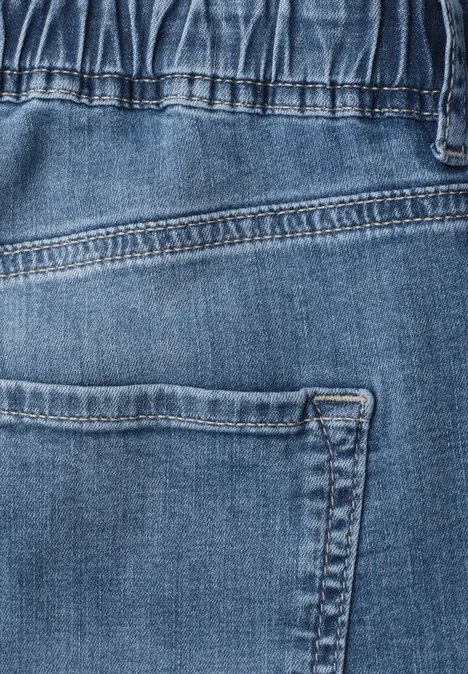 Gros plan sur un jean bleu avec poche arrière et coutures apparentes.
