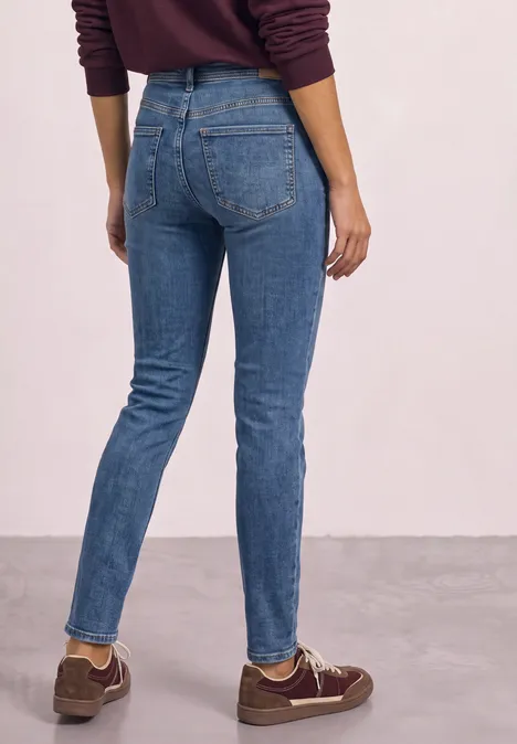 Person von hinten in blauen Skinny-Jeans und braunen Sneakern.