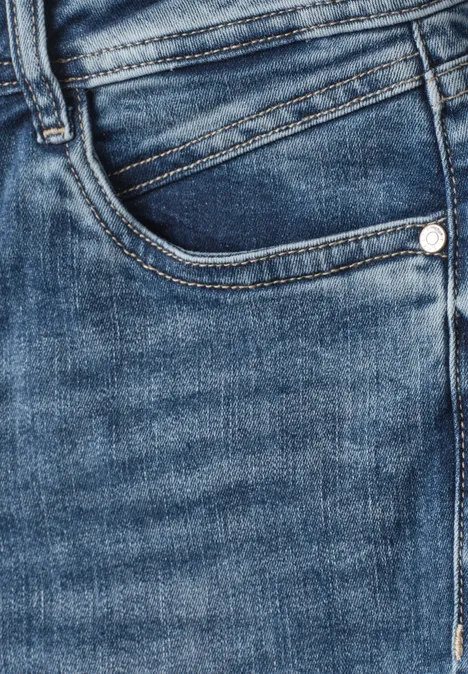 Jeansy Mid Waist z wąskimi nogawkami w stylu Slim Fit Medium Blue Soft Washed Zbliżenie niebieskich dżinsów, ukazujące przednią kieszeń i szwy.