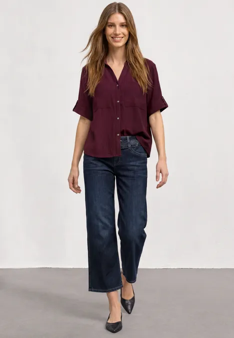 Jeans Culotte mit Gürteldetail Deep Blue Washed Frau in dunklem Hemd, weiten Jeans und spitzen Pumps vor neutralem Hintergrund.