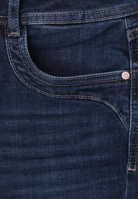 Nahaufnahme einer dunklen Jeanshose mit Gesäßtasche, Niete und sichtbaren Nähten.