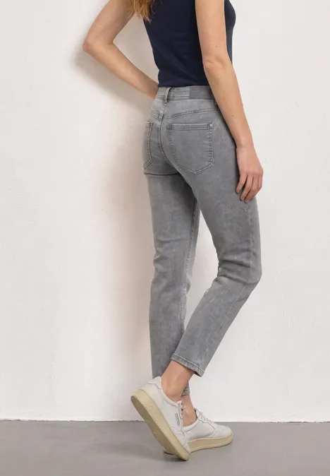 Eine Frau trägt eine stilvolle graue Jeans und weiße Plateausneaker.