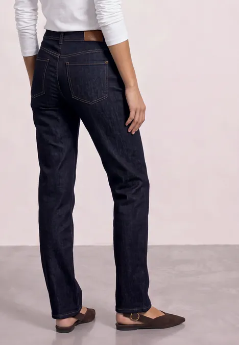 Person von hinten mit dunkelblauen geraden Jeans und braunen Ballerinas.