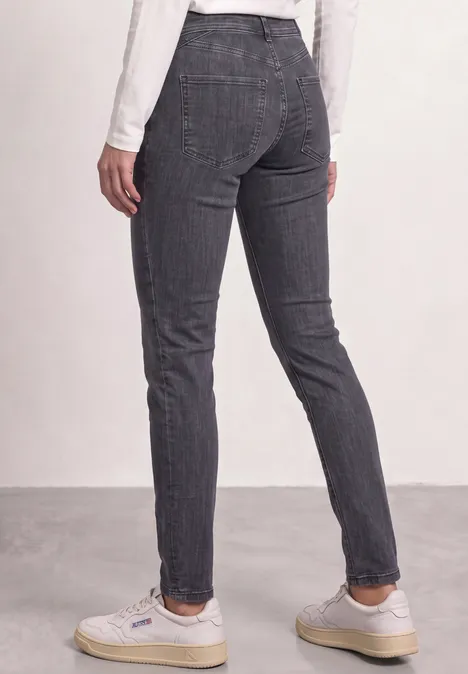 Achteraanzicht van een persoon met een donkergrijze, ruitjes slim fit broek en witte sneakers.