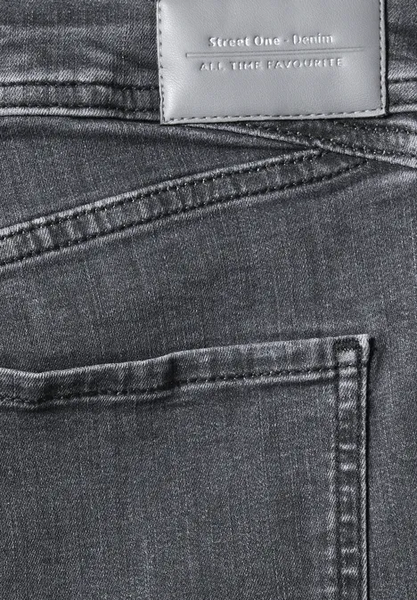 Close-up van de achterkant van een blauwe spijkerbroek met achterzak en lederen label.