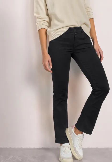 Mid Waist Slim Leg Jeans im Casual Fit Black Clean Washed Person in schwarzer Jeans und weißen Sneakers, Oberteil in hellem Farbton.