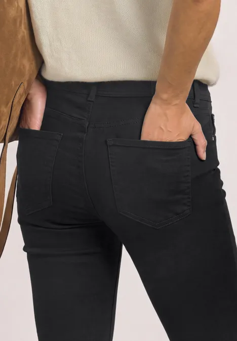Mid Waist Slim Leg Jeans im Casual Fit Black Clean Washed Person von hinten in schwarzer Jeans mit Händen in den Gesäßtaschen.