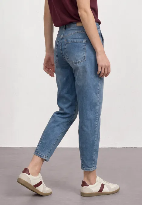 High Waist Barrel Leg Jeans im Loose Fit Medium Blue Random Wash Person von hinten in lockeren blauen Jeans und Sneakers vor weißem Hintergrund.