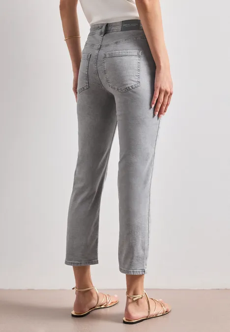 Rückansicht einer Person in hochgeschnittenen, grauen, knöchellangen Jeans mit geradem Bein und flachen Sandalen.