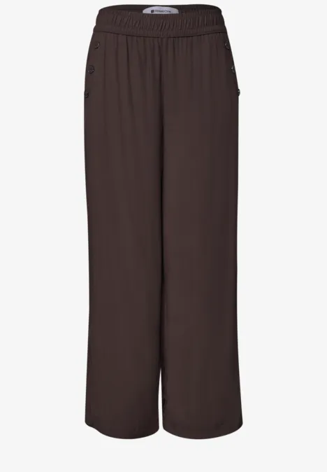 Pantalon marron foncé à jambes larges, taille haute et poches latérales zippées.