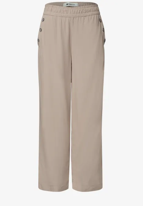 Beige, losse broek met elastische taille en knoopsluiting langs de zijkanten, ideaal voor vrije tijd.