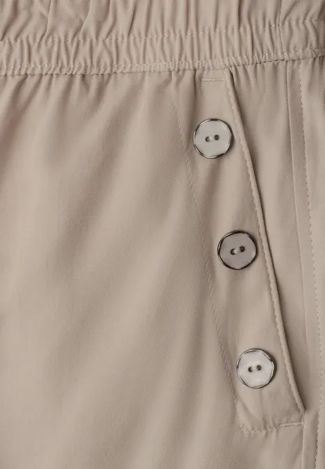 Beige broek met elastische taille en drie knopen aan de zijkant.