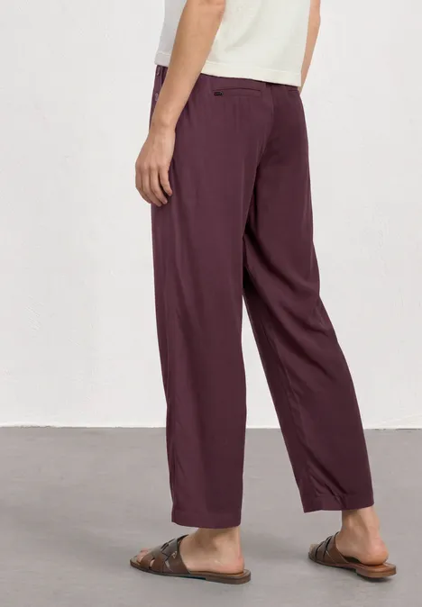 High Waist Wide Leg Hose im Loose Fit rustic rouge Person trägt weite dunkelrote Hose mit Taschen und braune Sandalen vor weißem Hintergrund.