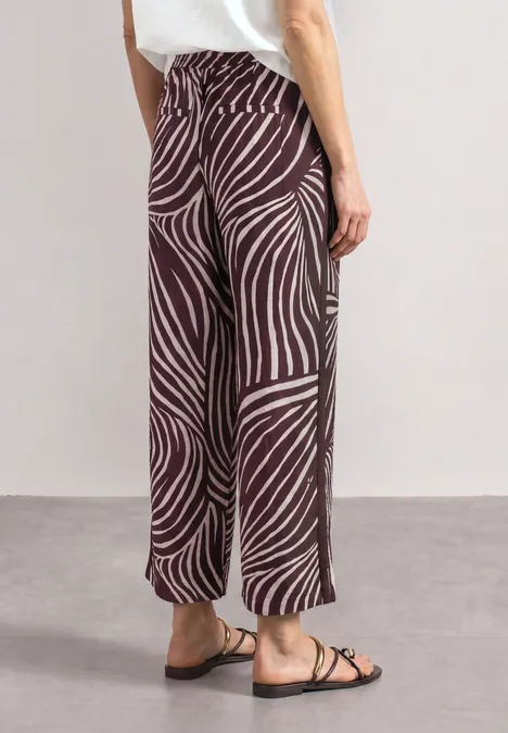 Wijde broek met bruin-beige zebraprint, rechte pasvorm, enkel-lang, gecombineerd met platte sandalen.