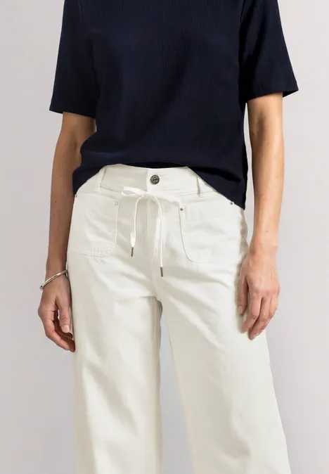 Straight Leg Hose in Washed-Optik off white Frau in schwarzem Kurzarmshirt und weißen, weiten Hosen.