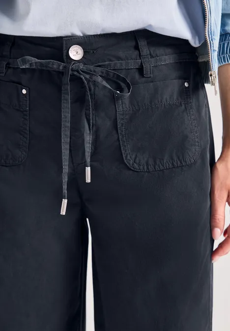 Schwarze, weite Hose mit Kordelzug an der Taille und aufgesetzten Fronttaschen.