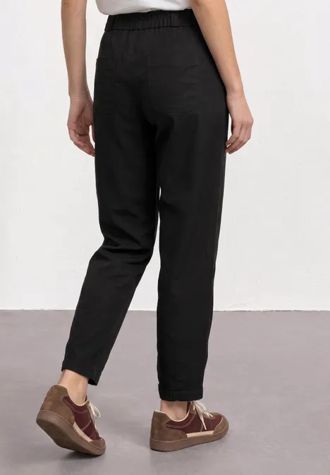 Persoon van achteren in een zwarte casual broek en bruine sneakers