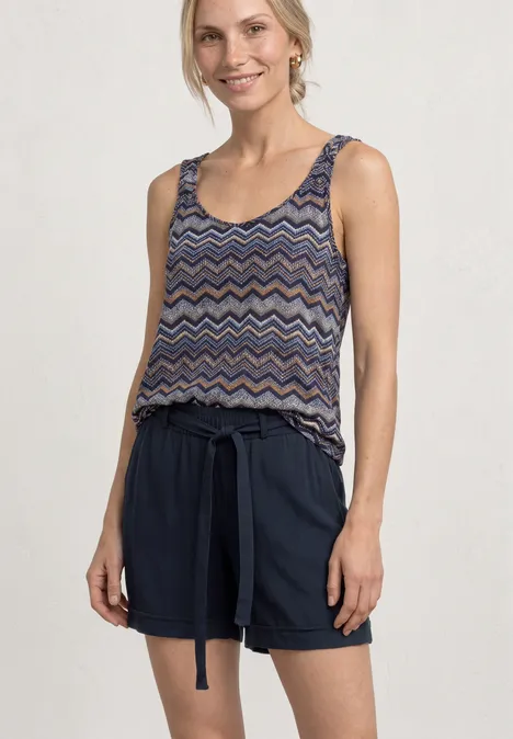 Vrouw in mouwloos topje met zigzagpatroon en marineblauwe short met ceintuur.