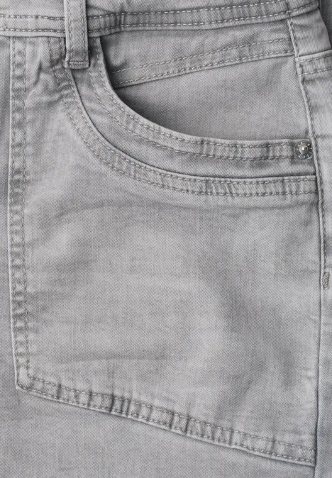 Gros plan d'un jean gris avec poche apparente et coutures fines.