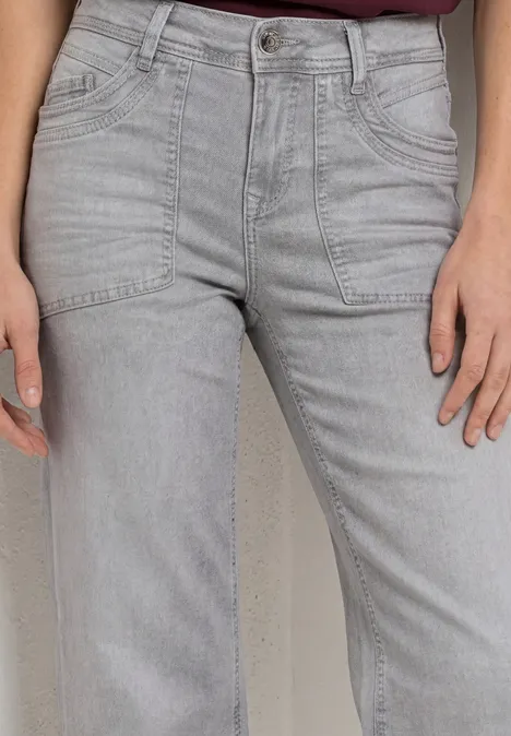 Gros plan sur une personne portant un jean gris clair taille haute à coupe droite.